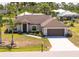 Beautiful one-story home featuring a well-manicured lawn, mature palm trees, and a two-car garage at 16094 Ortega Dr, Punta Gorda, FL 33955