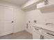 This modern laundry room features wood-look floors, a marble countertop, and white cabinets at 17130 Elder St, Port Charlotte, FL 33954