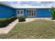 Close-up of a home's entrance with a paved walkway, vibrant blue exterior, and neatly trimmed hedges at 190 Casa Ln, Punta Gorda, FL 33950