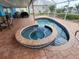 Close-up of an outdoor hot tub with adjacent swimming pool, surrounded by brick pavers within a screened enclosure at 190 Casa Ln, Punta Gorda, FL 33950