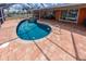 Inviting backyard with an oval shaped pool, hot tub, and brick patio at 190 Casa Ln, Punta Gorda, FL 33950