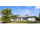 A charming, freshly painted home with a metal roof, black trim, and well-maintained landscaping at 19723 Midway Blvd, Port Charlotte, FL 33948