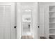 Hallway with a view to a white tiled bathroom with a lighted mirror and closet storage at 19723 Midway Blvd, Port Charlotte, FL 33948