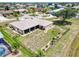 An aerial view of a single story home featuring an expansive fenced yard with tropical landscaping and circular driveway at 25379 Paladin Ln, Punta Gorda, FL 33983