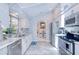 Modern kitchen features white cabinets, stainless steel appliances, and stylish white-washed brick accent wall at 25379 Paladin Ln, Punta Gorda, FL 33983