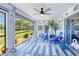 Relaxing screened patio features blue patio furniture, ceiling fans, and views of the landscaped yard at 25379 Paladin Ln, Punta Gorda, FL 33983