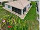 Back exterior view of house showing large screened-in lanai, landscaping, and surrounding yard at 26111 Feathersound Dr, Punta Gorda, FL 33955