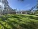 Exterior of home showing covered porch and spacious backyard with trees at 27128 Aloha Dr, Punta Gorda, FL 33955