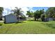 View of expansive backyard showcasing a well-maintained lawn, shade trees, screened in porch and outbuildings at 2805 Gussie St, Punta Gorda, FL 33950