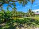 A well kept lawn features canal access and mature banana and palm trees at 3616 Allapatchee Dr, Punta Gorda, FL 33950