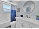 Bright bathroom featuring a shower/tub combo and single sink vanity with a large, round mirror at 3616 Allapatchee Dr, Punta Gorda, FL 33950