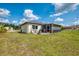 A view of a grassy backyard featuring a screened in patio at 4044 S Salford Blvd, North Port, FL 34287
