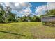 A large grassy backyard with some mature trees and a screened-in patio at 4044 S Salford Blvd, North Port, FL 34287
