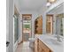 Bright bathroom with wooden vanity, a wicker shelf and tile floors near shower and toilet at 4317 Mccullough St, Port Charlotte, FL 33948