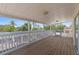 A covered porch with wood flooring and white railings looks out to tropical vegetation at 4317 Mccullough St, Port Charlotte, FL 33948