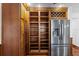 Spacious pantry with custom wood shelving, cabinets, and wine rack located adjacent to stainless steel refrigerator at 4317 Mccullough St, Port Charlotte, FL 33948