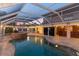 Evening view of the covered pool with a rock waterfall, bar area, and inviting ambiance at 4317 Mccullough St, Port Charlotte, FL 33948