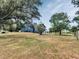 Wide backyard featuring mature trees and a blue house with a deck creating a serene outdoor space at 6421 Grove Blvd, Punta Gorda, FL 33982