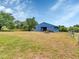 View of a large barn with an open side and a fenced pasture with neatly stacked wood at 6421 Grove Blvd, Punta Gorda, FL 33982