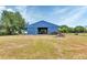 View of large blue barn with open entry and fenced pasture and some stacked wood at 6421 Grove Blvd, Punta Gorda, FL 33982