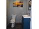 Elegant half-bath featuring a modern vanity with blue cabinetry and stylish fixtures, complemented by a coastal-themed artwork at 6421 Grove Blvd, Punta Gorda, FL 33982