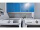 Functional laundry room with overhead blue storage cabinets, and new washer and dryer units at 6421 Grove Blvd, Punta Gorda, FL 33982