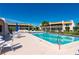 Community pool with lounge chairs, tables, and umbrellas, surrounded by well-maintained landscaping at 1080 Bal Harbor Blvd # 12C, Punta Gorda, FL 33950