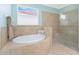 Well-lit bathroom showcasing a soaking tub and glass enclosed shower with tiled walls at 11666 Parrotfish St, Venice, FL 34292