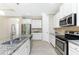 White kitchen featuring stainless steel appliances, granite counters, and modern fixtures at 11666 Parrotfish St, Venice, FL 34292