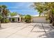 Charming single-story home featuring an expansive paved driveway and lush tropical landscaping at 155 Donna Ct, Punta Gorda, FL 33950