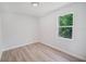 Inviting bedroom with neutral walls, wood-look flooring, and a window providing serene natural light at 16218 Chamberlain Blvd, Port Charlotte, FL 33954