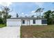 Charming single-story home with a modern white exterior and a well-manicured front lawn at 16218 Chamberlain Blvd, Port Charlotte, FL 33954