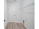 Functional laundry room with wood-look floors, wire shelving, utility sink and a white door at 16218 Chamberlain Blvd, Port Charlotte, FL 33954