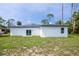 View of back exterior with bright white walls, sliding glass door, and an expansive green yard at 17197 Russell Ave, Port Charlotte, FL 33954