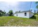 Exterior of house with large grassy area, back of screened-in lanai, and small window on side at 17197 Russell Ave, Port Charlotte, FL 33954