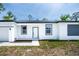 Front exterior view features the front door and two windows, with a grey accent wall and garage on the left at 17197 Russell Ave, Port Charlotte, FL 33954