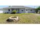Backyard featuring a screened lanai, green grass, neutral-colored exterior, and an inviting fire pit area at 19468 Edgewater Dr, Port Charlotte, FL 33948
