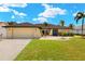 Inviting single-story home featuring a manicured lawn, palm trees, and a neutral-toned exterior paint at 2152 Taiwan Ct, Punta Gorda, FL 33983