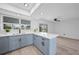 Open kitchen features a large countertop and bar with grey cabinets, modern lighting, and wood flooring at 2166 Beacon Dr, Port Charlotte, FL 33952