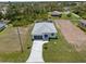 Aerial view of a modern home with grey roofing, a two-car garage, and a long driveway surrounded by grass at 223 Australian Dr, Rotonda West, FL 33947