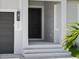 A close up of a front entrance with a black front door, light fixture, garage door, and small garden at 223 Australian Dr, Rotonda West, FL 33947