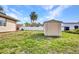 Fenced backyard with a storage shed, grassy lawn, and mature palm trees at 2300 Carpenter Ln, North Port, FL 34286