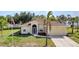 Charming single-story home featuring a manicured lawn, lush landscaping, and an attached two-car garage at 2300 Carpenter Ln, North Port, FL 34286