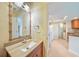 Updated bathroom featuring wood vanity, decorative mirror, and convenient access to the kitchen and laundry areas at 2486 Caring Way # 14A, Port Charlotte, FL 33952