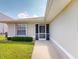 Inviting home entrance featuring a screened doorway, well-maintained lawn and lush flowering bushes at 26333 Nadir Rd # 111, Punta Gorda, FL 33983