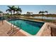 Community pool overlooks a peaceful lake, surrounded by lush landscaping and plenty of lounge chairs at 26333 Nadir Rd # 111, Punta Gorda, FL 33983