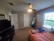 Cozy bedroom features ceiling fan, neutral walls, a full-length mirror and a large window at 2739 Sherman Oak Dr, North Port, FL 34289