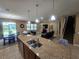 Open-concept kitchen with granite island, stainless sink and view of the living room and dining area at 2739 Sherman Oak Dr, North Port, FL 34289