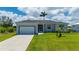 Charming single-story home featuring a two-car garage, lush lawn, and tropical palm trees at 3302 Palm Dr, Punta Gorda, FL 33950