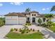 Elegant Mediterranean-style home featuring a three-car garage, a tile roof, and meticulously manicured landscaping at 3353 Sandpiper Dr, Punta Gorda, FL 33950